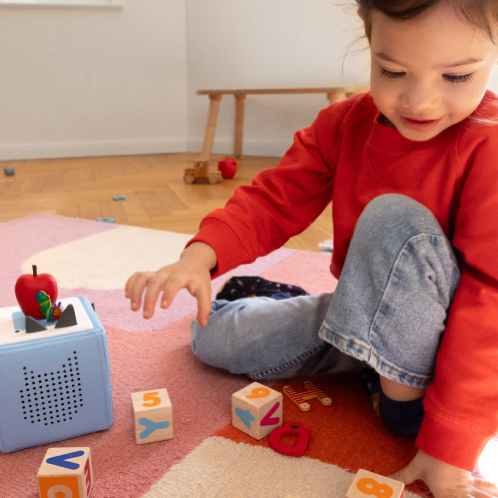 Child playing with educational toys on a pink rug