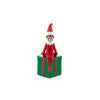 A Christmas elf figurine wearing a red outfit and hat, sitting on a green gift box with red ribbon details, isolated on a white background.
