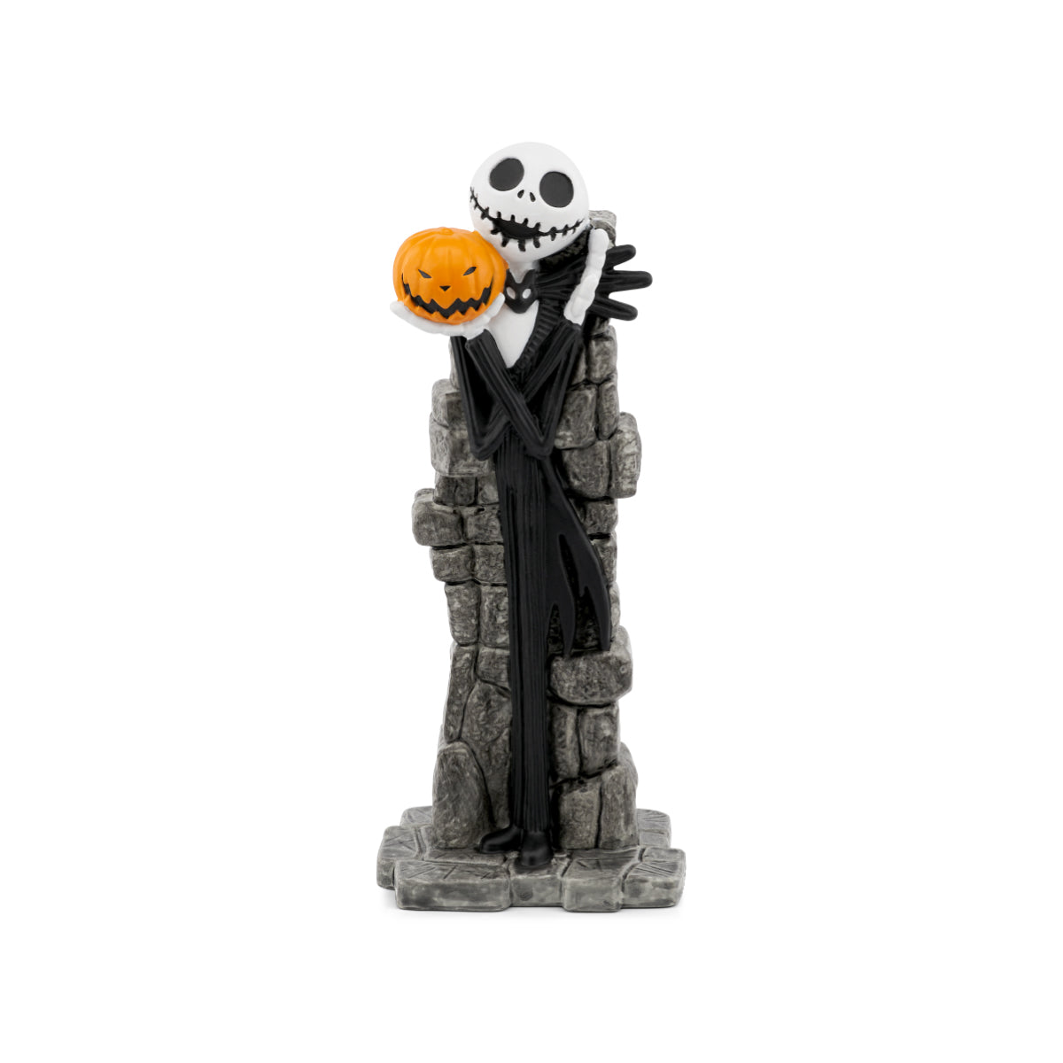 A Jack Skellington figurine from The Nightmare Before Christmas, standing on a gray stone tower and holding an orange jack-o'-lantern pumpkin, photographed against a solid white background.