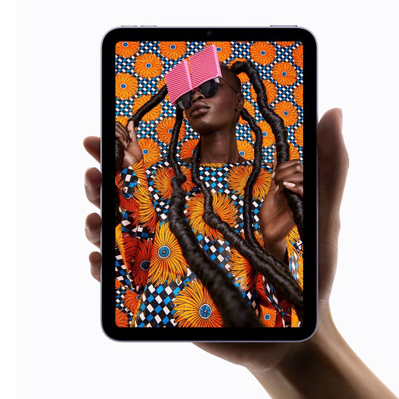 Hand holding the Apple iPad Air with an image of a person wearing a patterns dress with orange flower motive.
