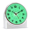 Silver alarm clock with green glowing face on a white background