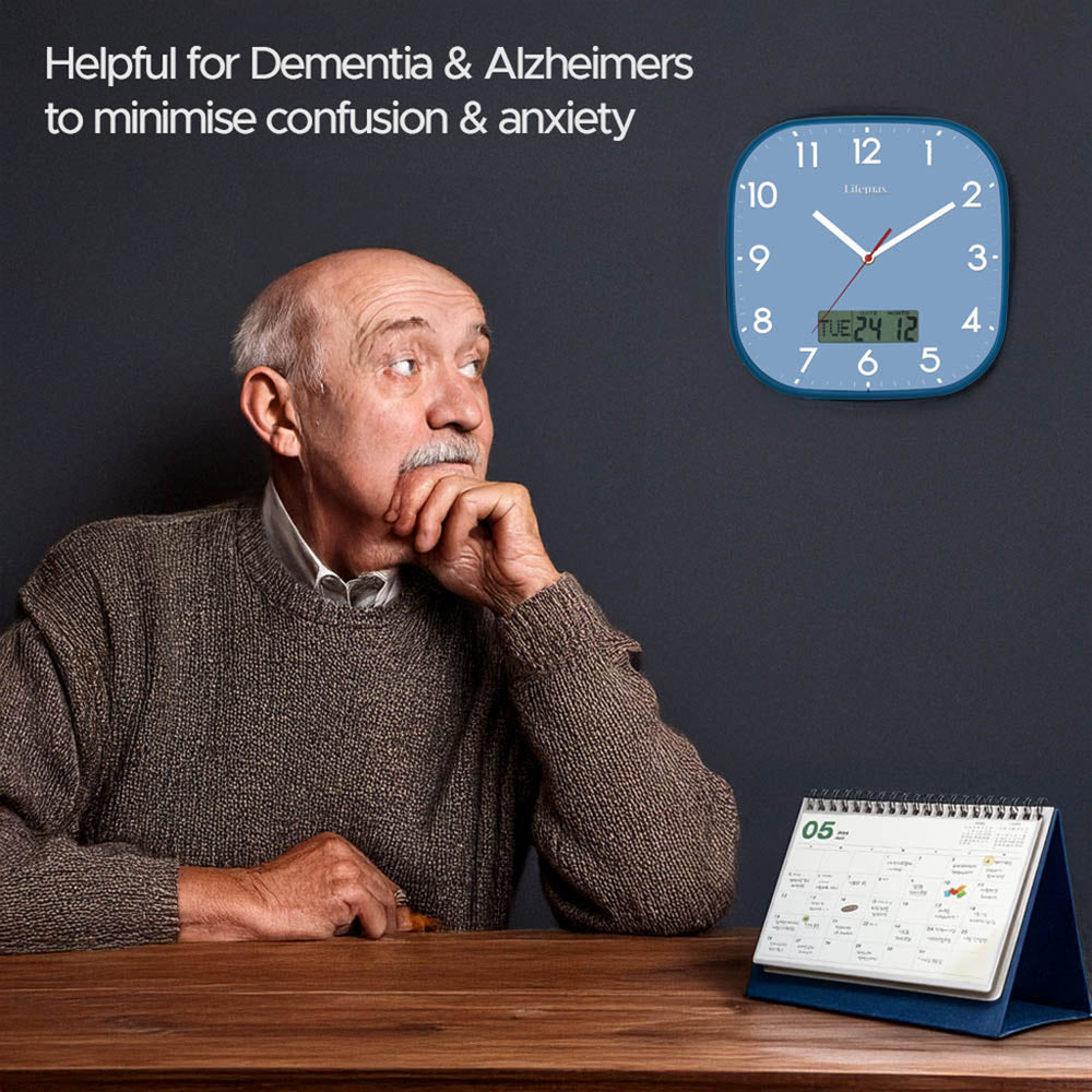 An older man sits at a wooden table against a dark gray wall, looking upward toward a blue wall clock with a digital date display. A small stand-up calendar sits on the table.