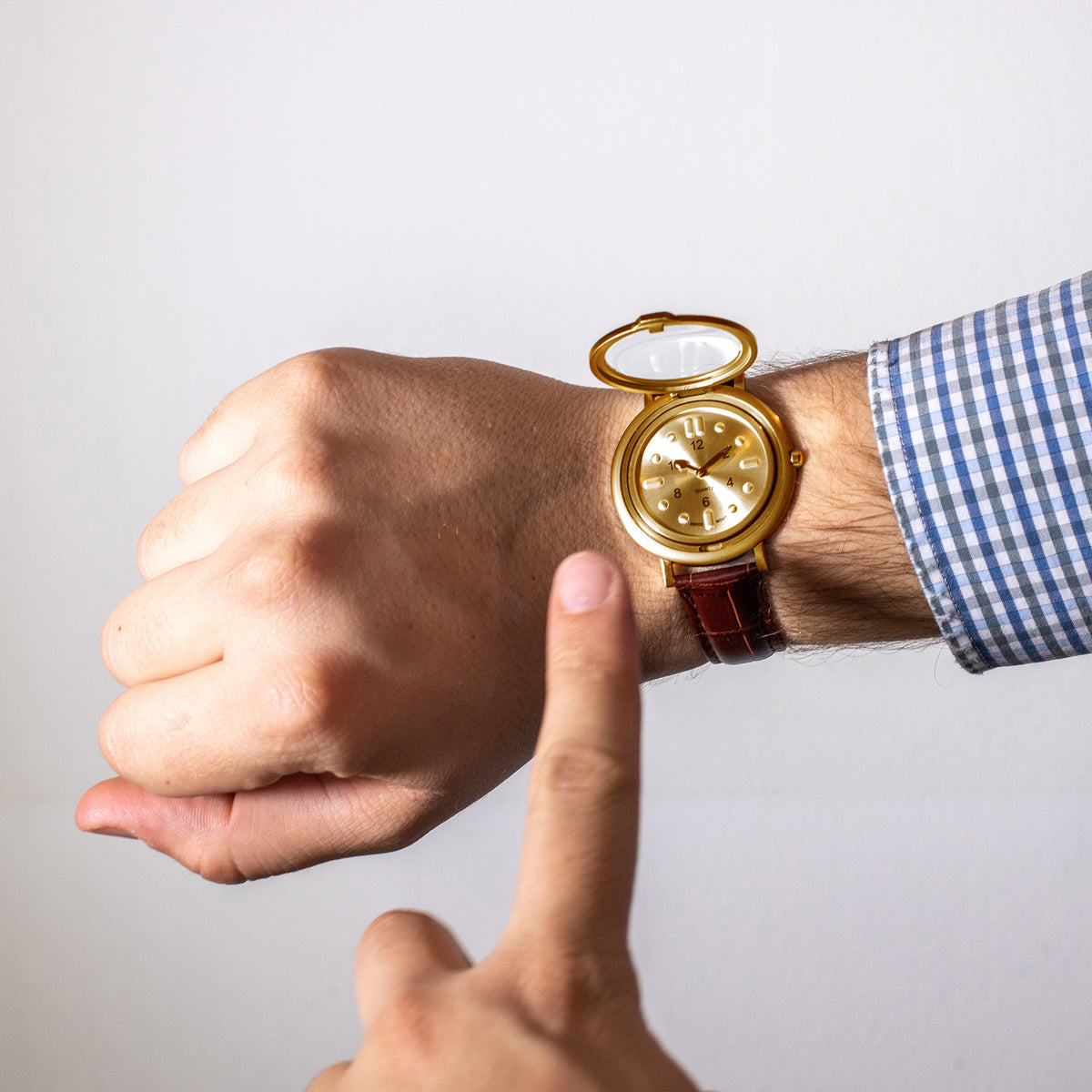 Watch on wrist with lid open and a finger pointing at dial