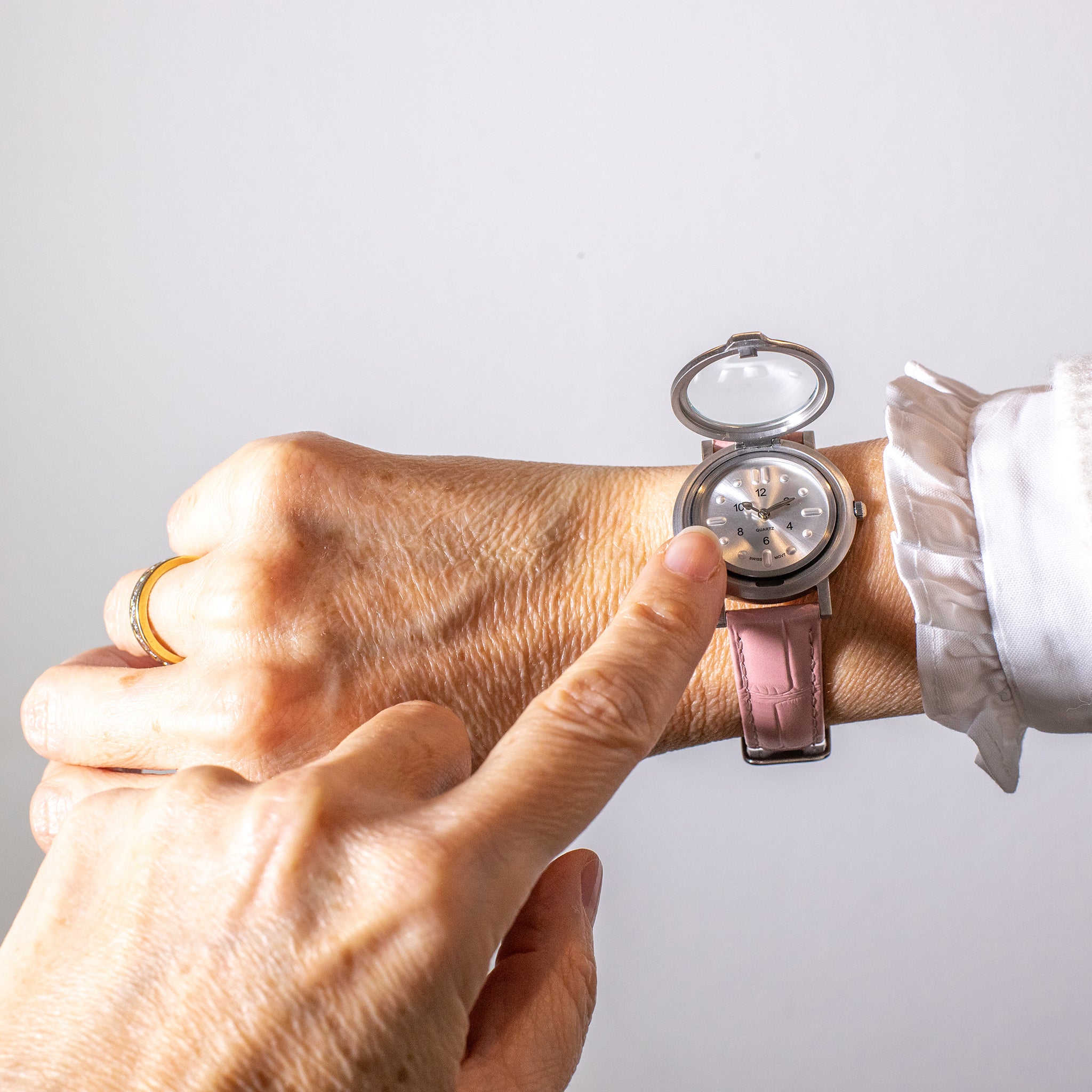 Watch on wrist with lid open and a finger pointing at dial