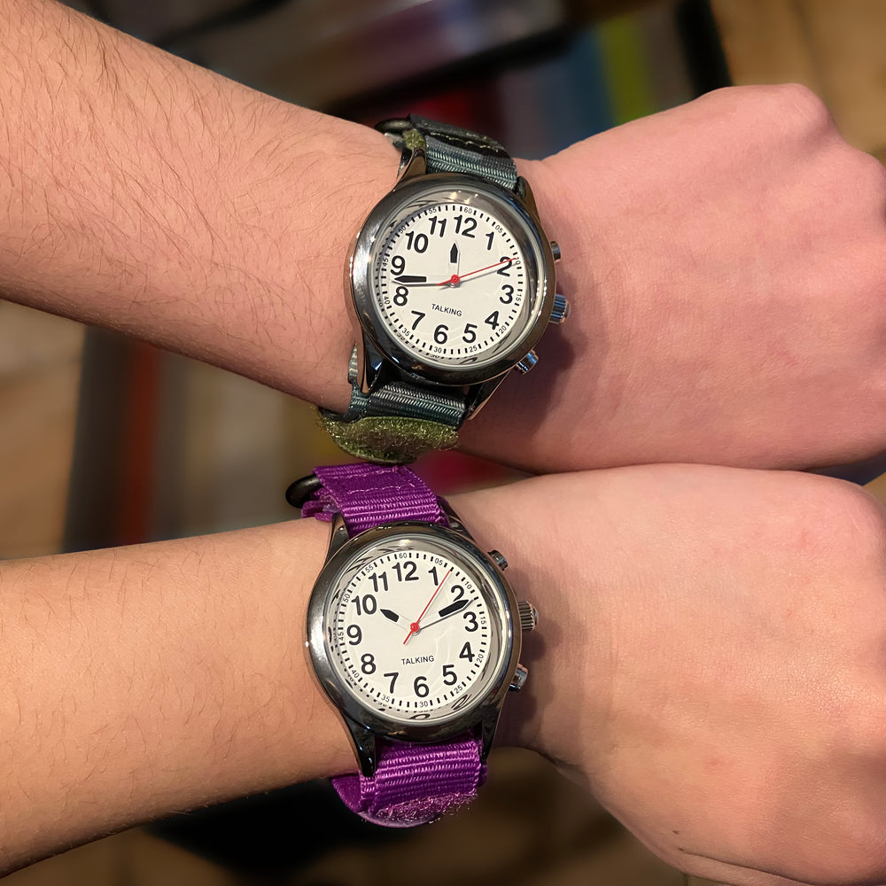 Two children holding their wrists next to each other, each wearing a talking children's watch with canvas strap.