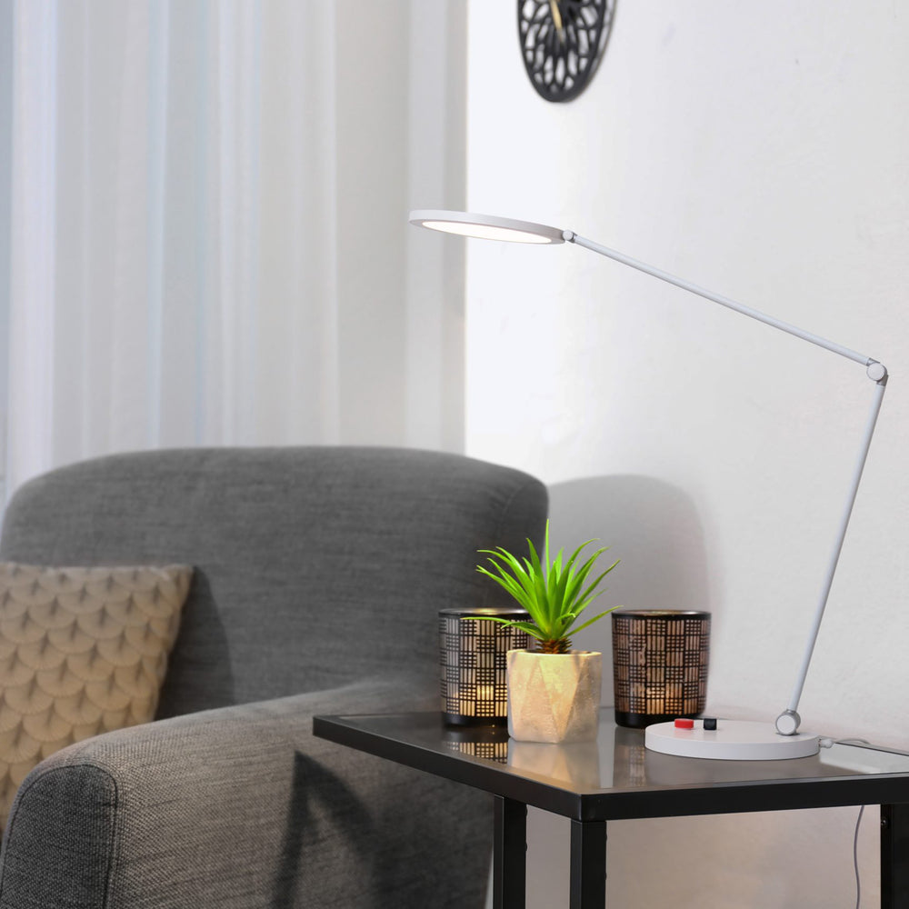 Daylight Tricolor lamp on a side table, shining on a small pot plant.