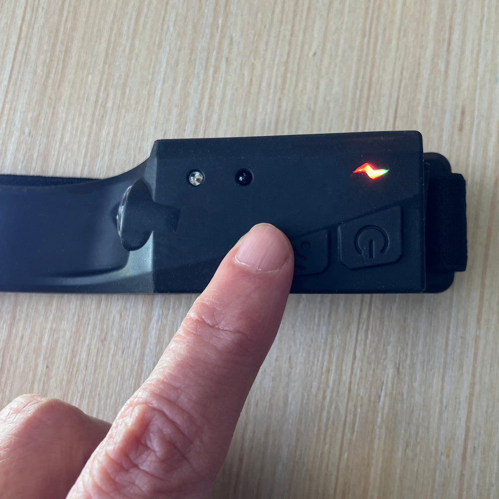 Close-up of sensor unit showing the power button, sensor button, and small light which indicates power and sensor status. A finger hovers over the sensor button.