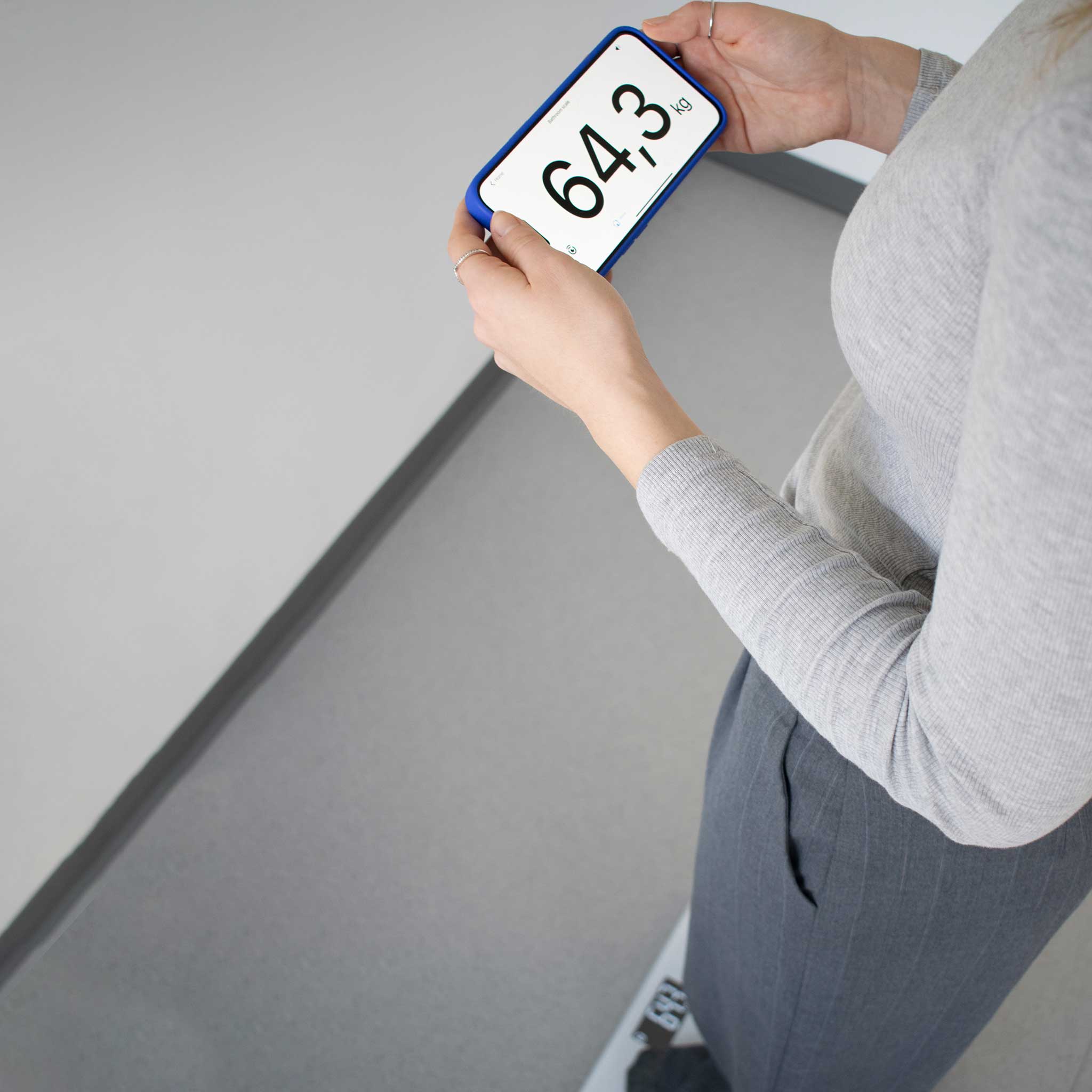 Person holding a digital weight display with a white background