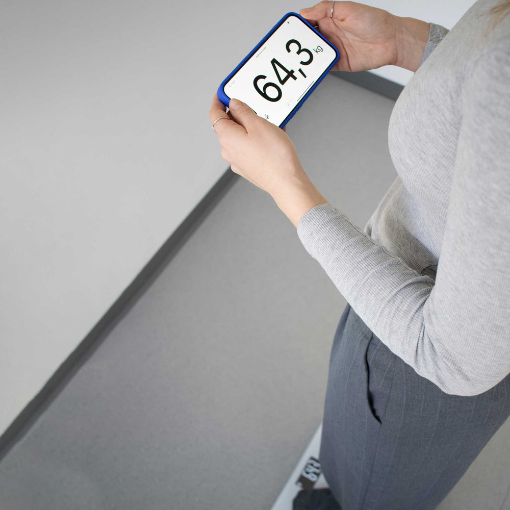 Person holding a digital weight display with a white background