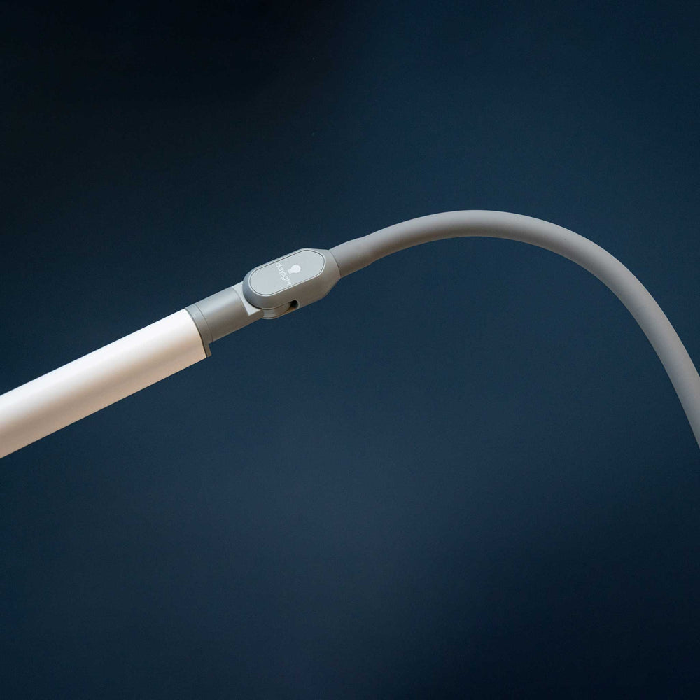 A close-up of a flexible white flexible arm with a gray adjustable joint and a small white button, set against a dark navy blue background.