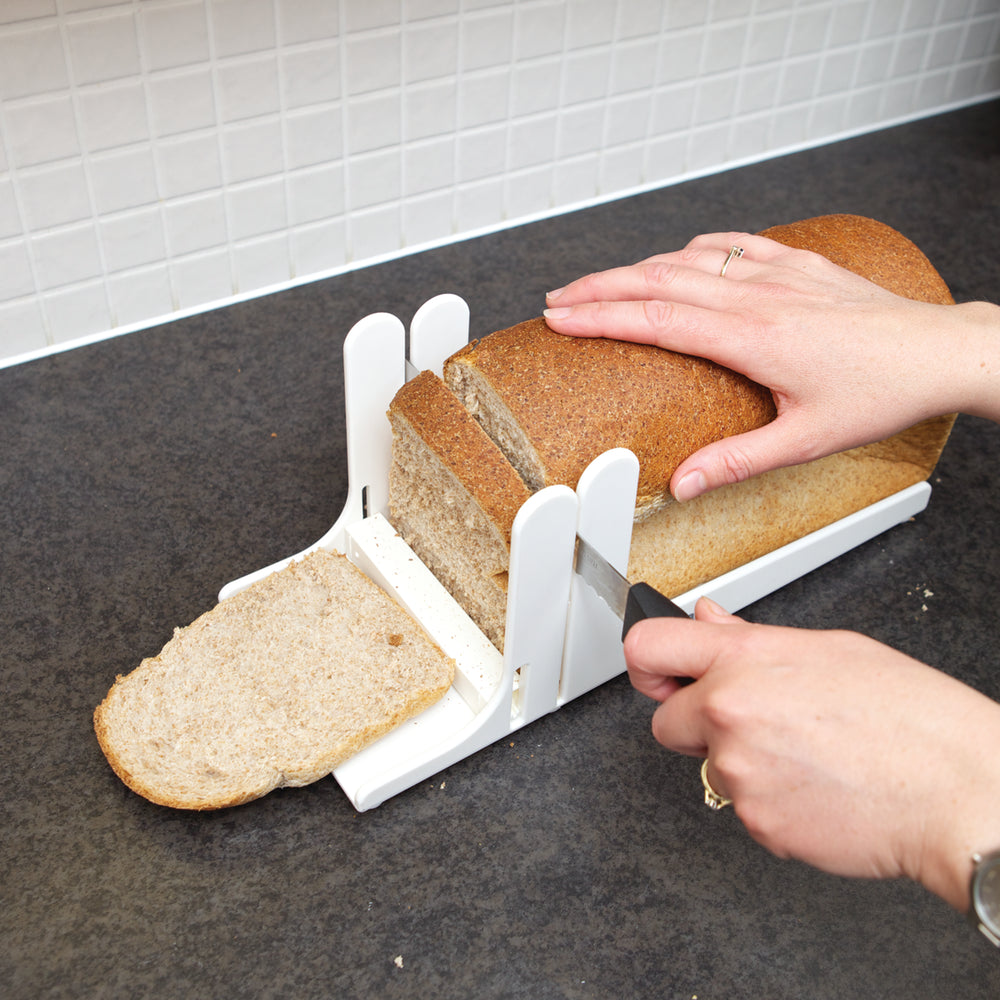 A person using the guide to slice a loaf of bread