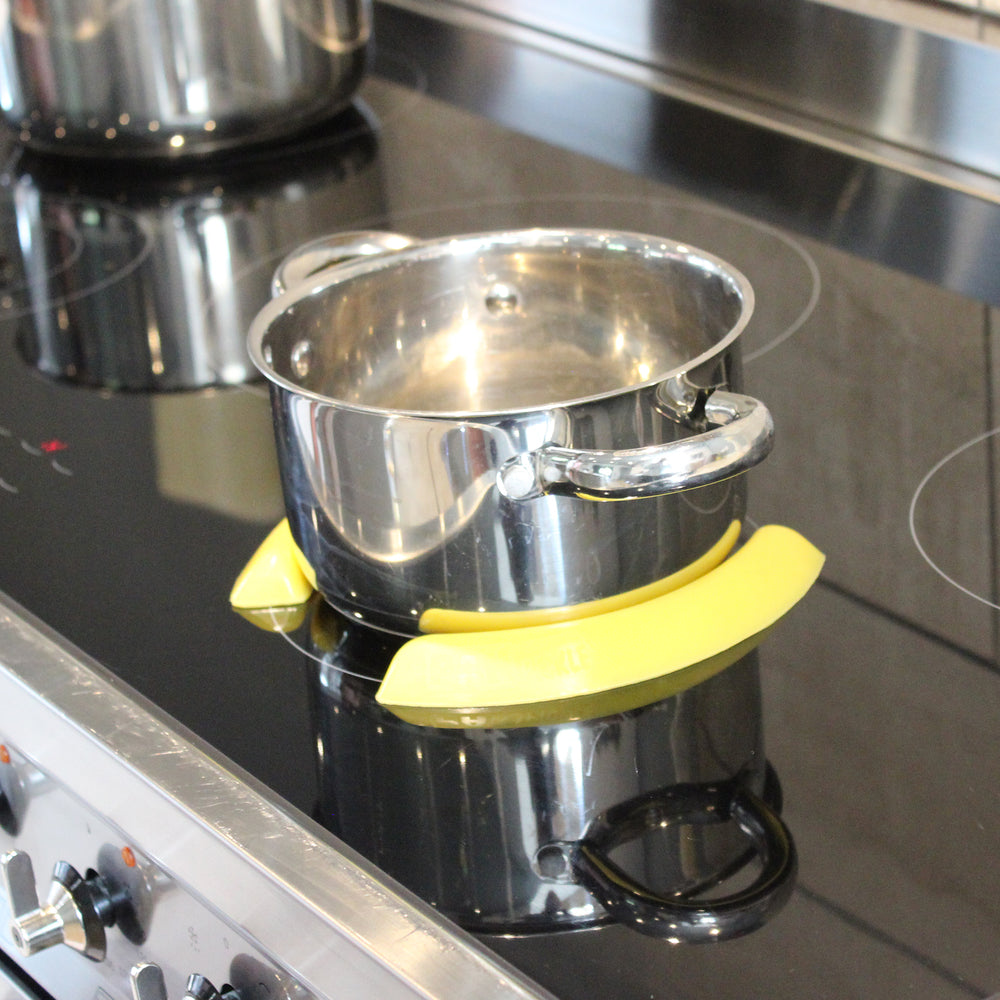 Pan on an induction hob held in place by yellow pan pickles