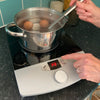A person uses the tactile power button to start boiling eggs on the RNIB Talking induction hob.