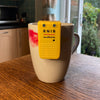 A white and red mug on a wooden table top. The liquid level indicator is positioned on the cup ready for measuring liquid.