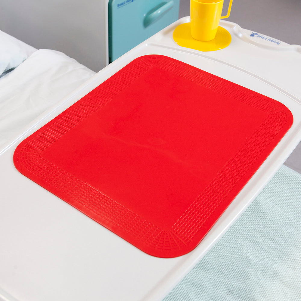 Rectangular red dycem mat on a hospital bed table