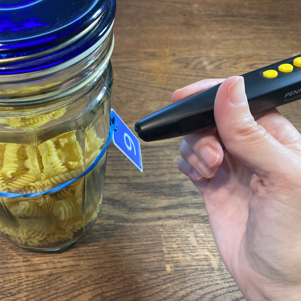 Someone using the PenFriend to identify a glass food storage jar