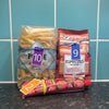 Rubber band fobs attached to groceries (bag of pasta, bag of ground coffee, tube of tomato paste) on a kitchen worktop