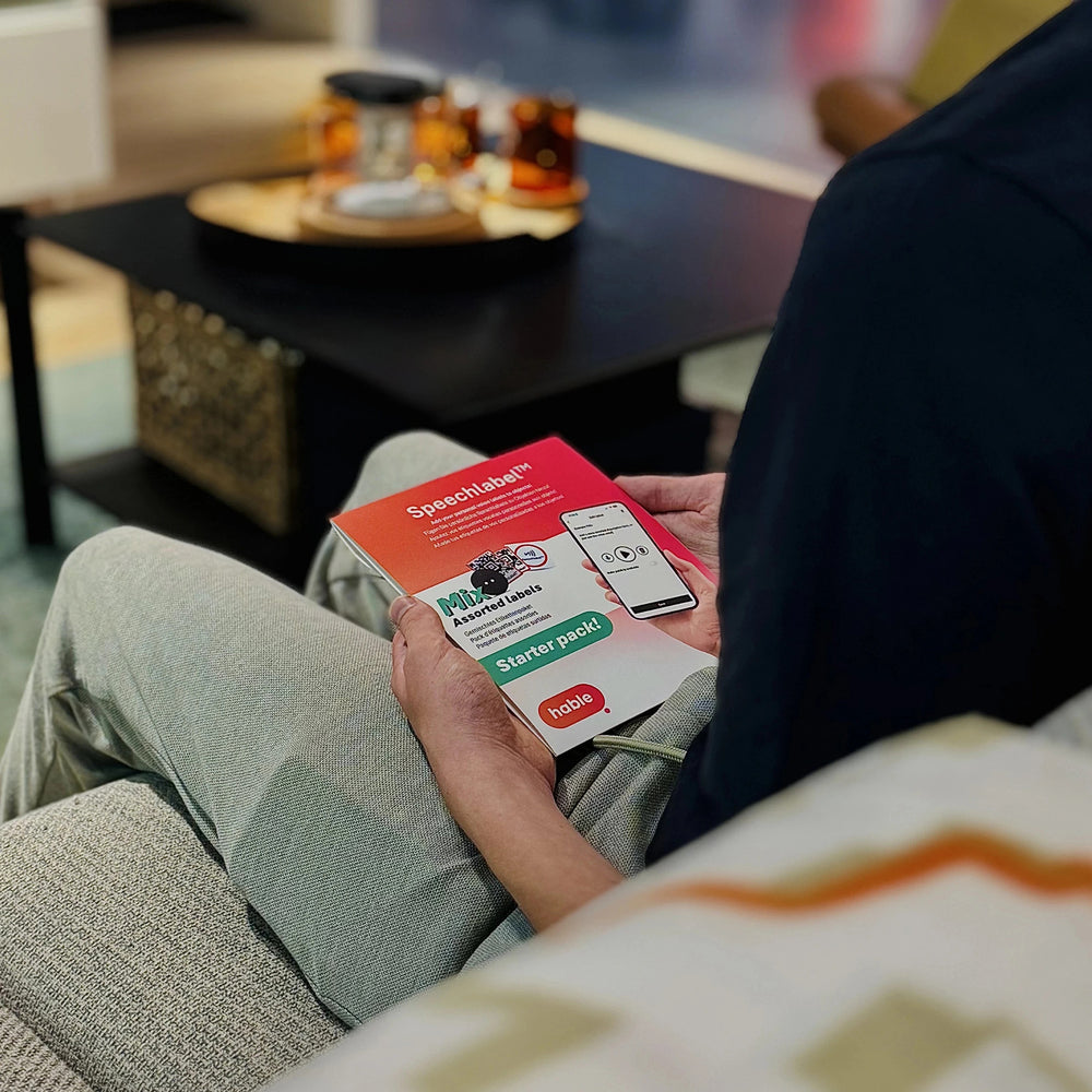 Person sitting on a couch holding a pack of Speechlables.