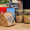 Various food products, including bread and cereals in jars with small Speechlables stuck to each for identification.