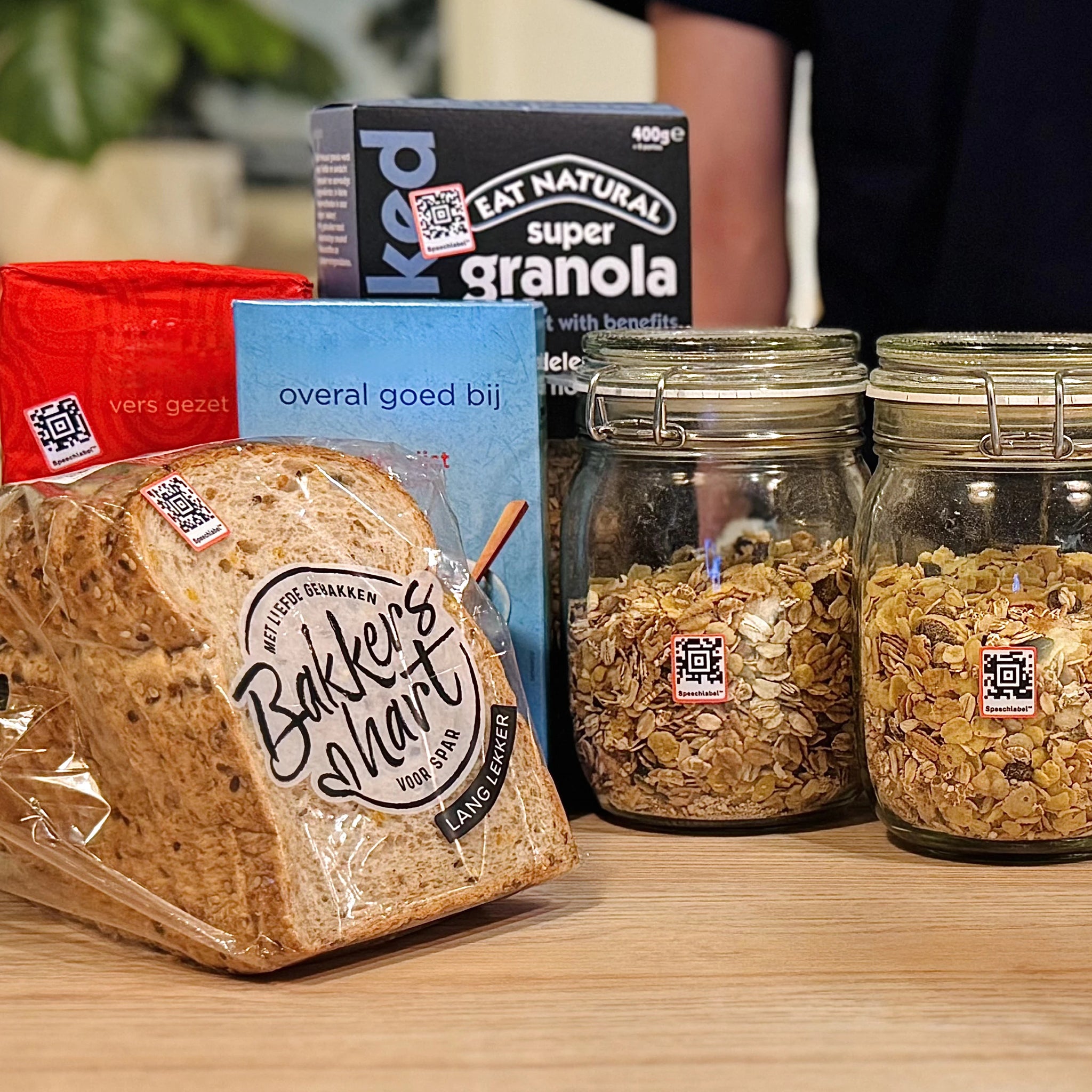 Various food products, including bread and cereals in jars with small Speechlables stuck to each for identification.