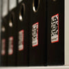 Black binders with red labels and QR codes on a shelf.