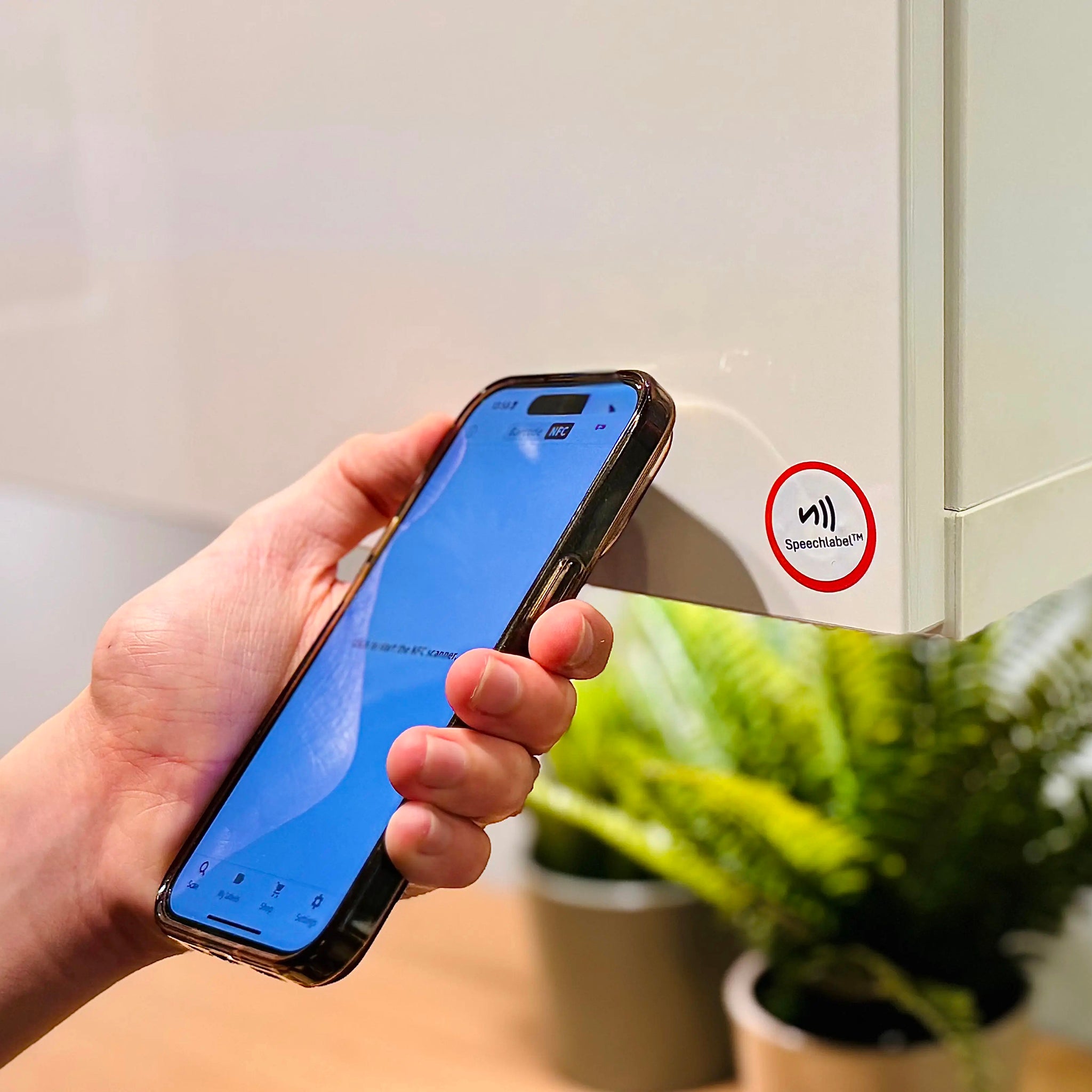 Hand holding a smartphone scanning one of the NFC labels on a cupboard door.
