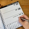 Calendar page showing February to March 2026 with a hand holding a pen.