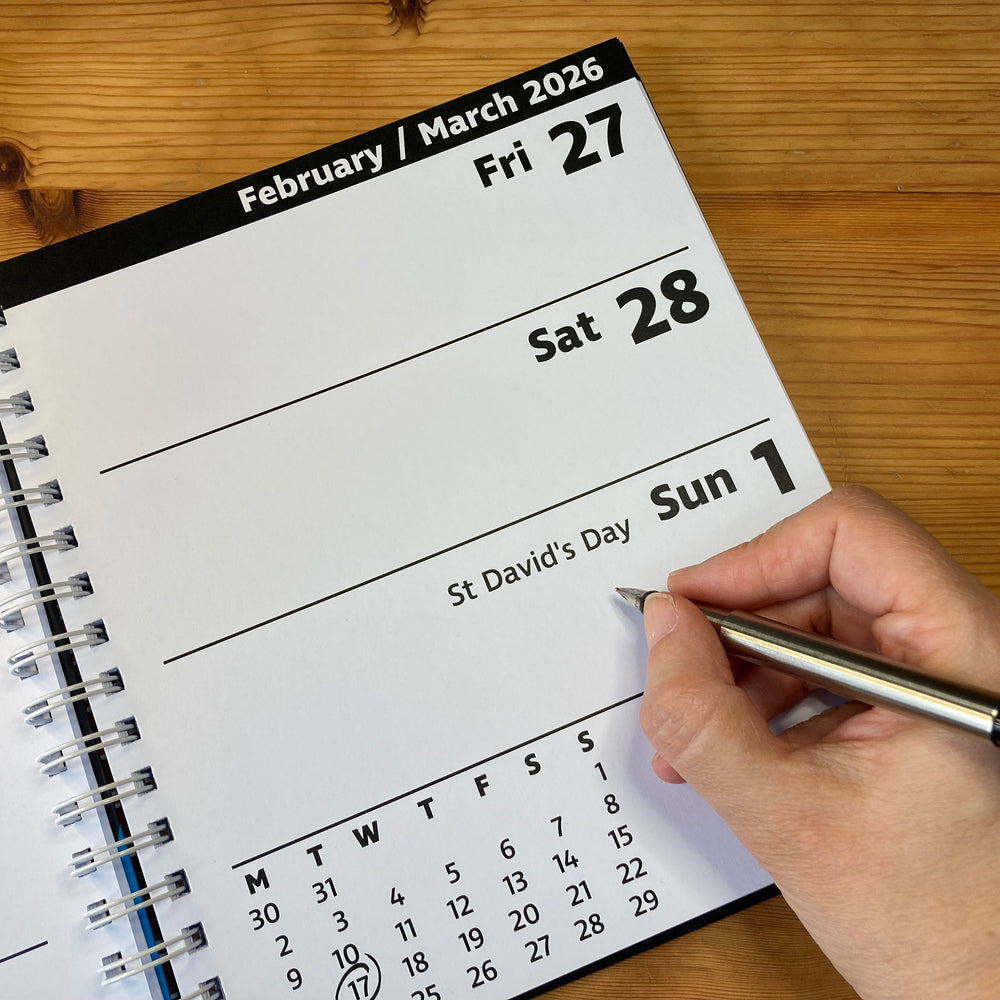Calendar page showing February to March 2026 with a hand holding a pen.