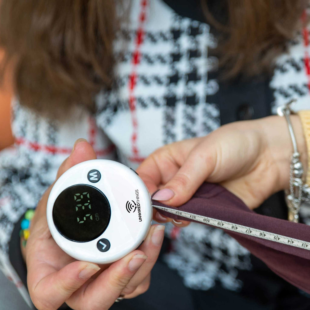 Person using the tape measure to measure a piece of clothing.
