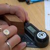 Person using a digital angle measure to measure a wooden block on a wooden surface.