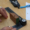 Wooden block with a hole being measured on a wooden table with a angle measure.