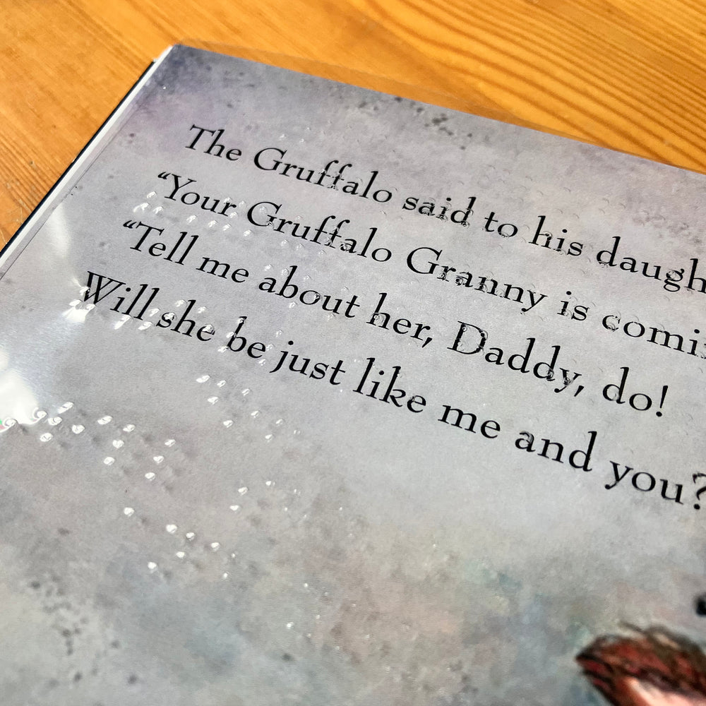 Braille on a clear sheet over the text and illustrations of a page of Gruffalo Granny.
