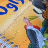 Close-up of braille on the page with a colorful bird illustration on a yellow background.