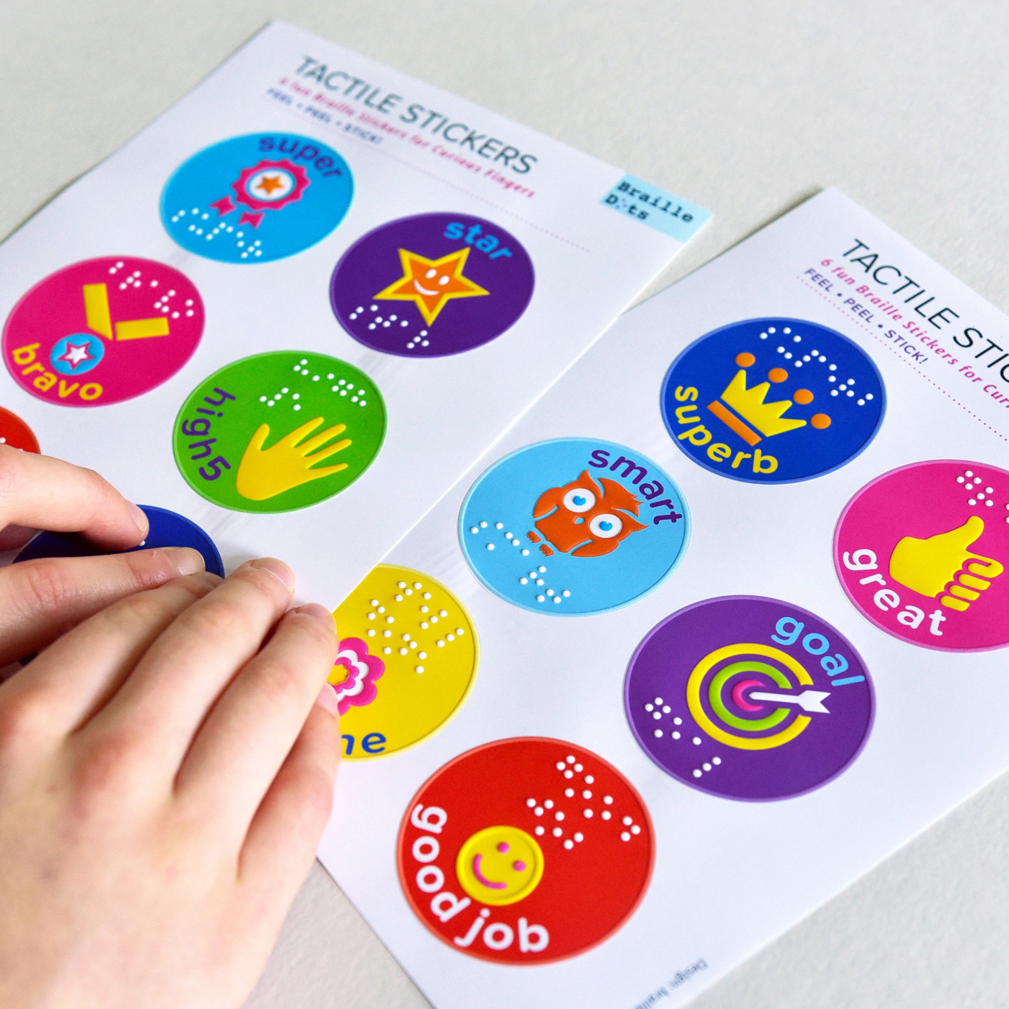 Two sheets of reward stickers with a person reading the braille
