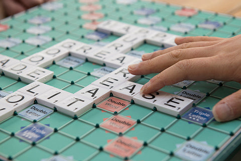 Someone reading braille Scrabble tiles on a Scrabble board by touch