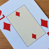 Close-up showing the pale yellow centre of the 2 of diamonds card with two diamonds. Outside the pale yellow rectangle the card has a large 2 and red diamond in the top left and bottom right corners.