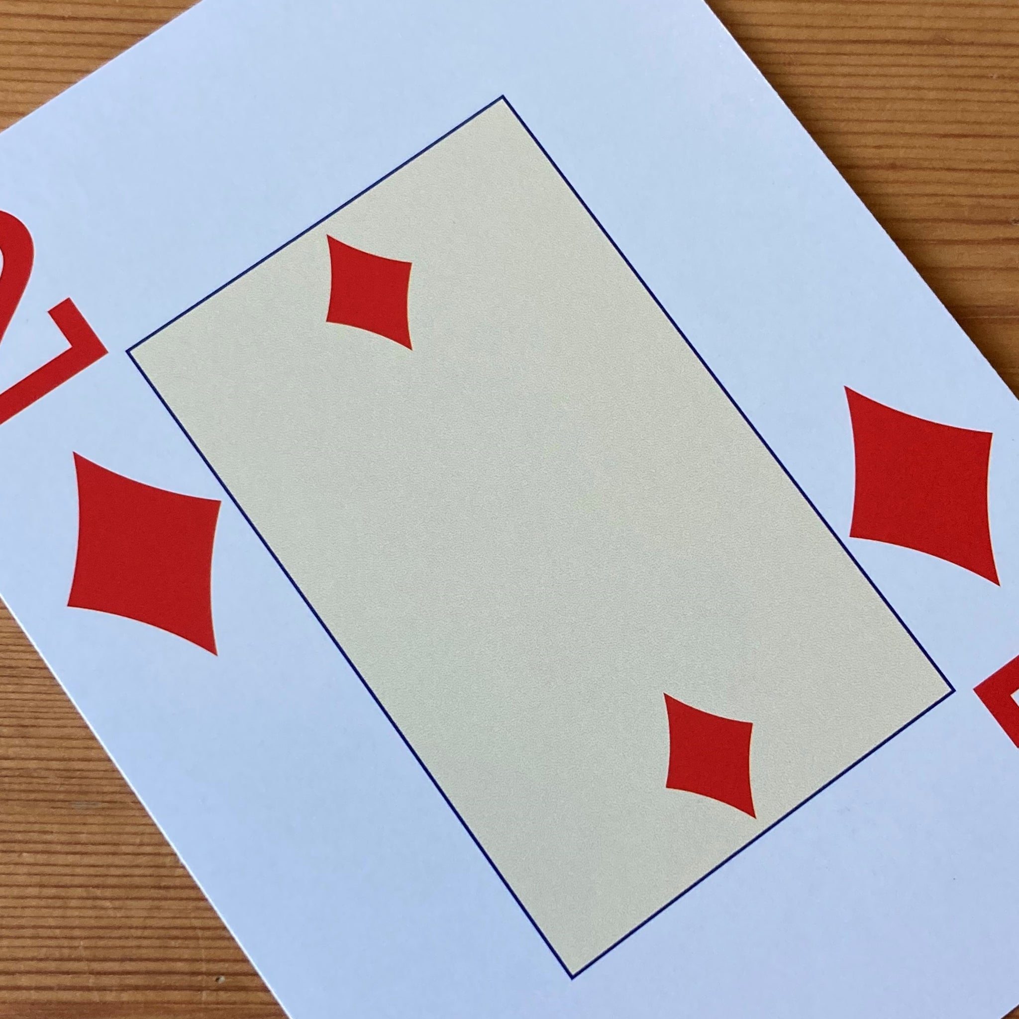 Close-up showing the pale yellow centre of the 2 of diamonds card with two diamonds. Outside the pale yellow rectangle the card has a large 2 and red diamond in the top left and bottom right corners.