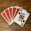 Six cards fanned out on a table showing the red backs and one showing its face