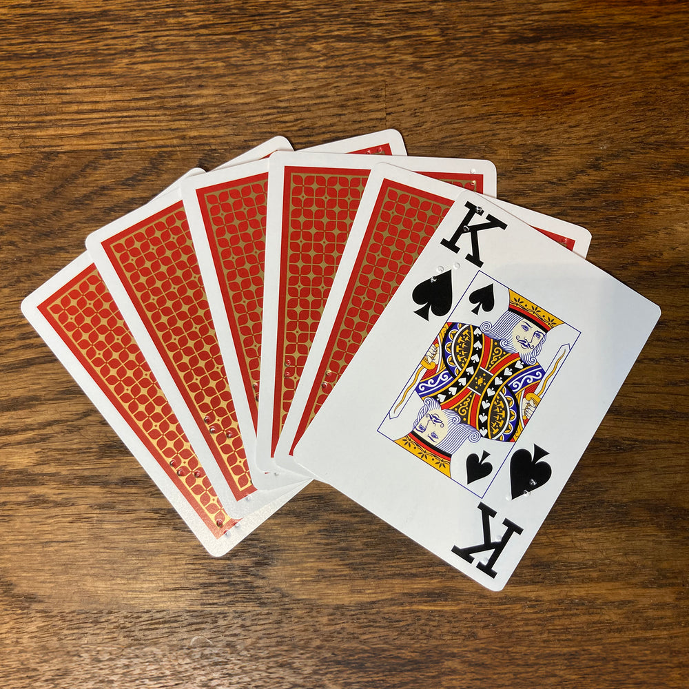 Six cards fanned out on a table showing the red backs and one showing its face