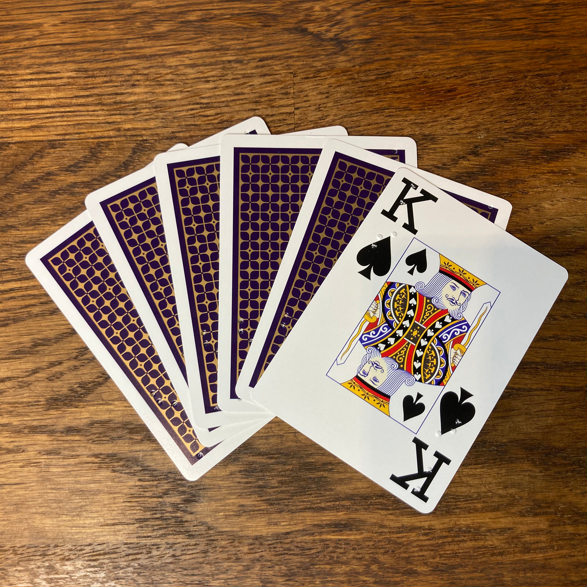 Six cards fanned out on a table showing the blue backs and one showing its face