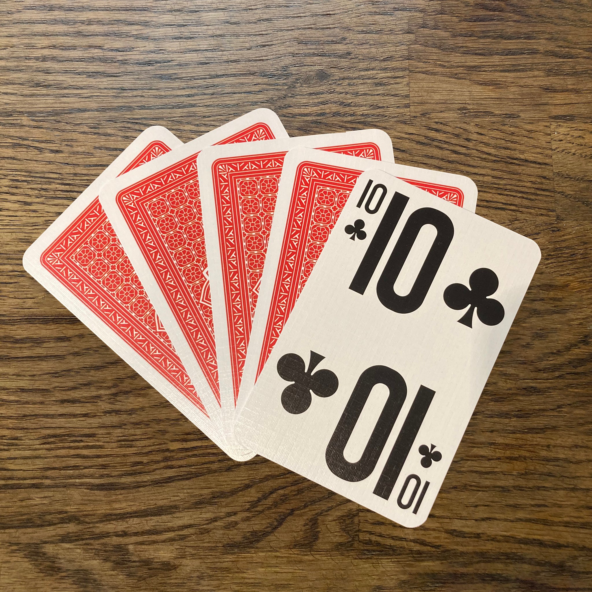 Large print playing cards fanned out showing the front of the 10 card and back of the red pack.