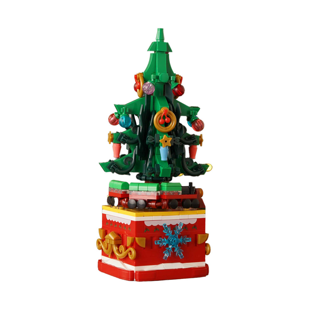 A toy building-block Christmas tree sculpture on a red gift box base, photographed against a plain white background.