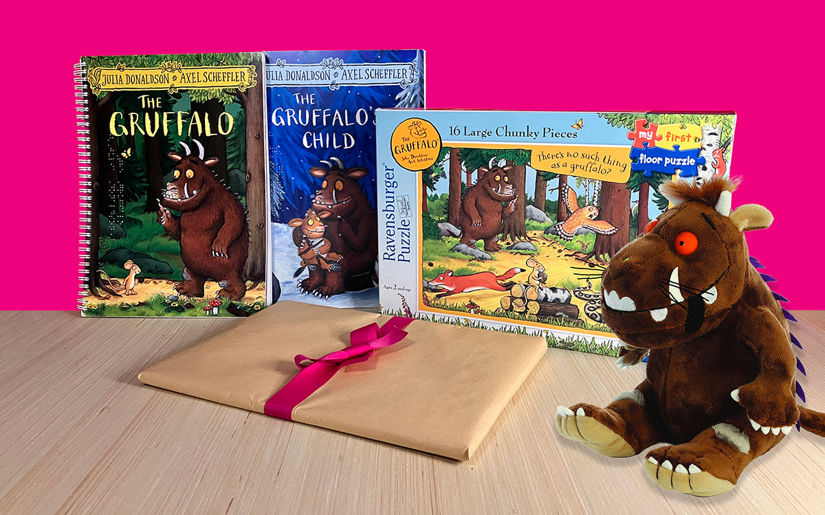 Collection of Gruffalo products with a hot pink background: braille and print editions of The Gruffalo and The Gruffalo's Child, a wrapped-up braille and print copy of Gruffalo Granny which launches on 10 September 2026, a Gruffalo floor puzzle, and a Gruffalo plush toy.