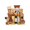 A gourmet gift hamper arranged in a woven wicker basket on a white background, featuring two wine bottles, a glass of red wine, cookies, biscuits, and packaged snacks from brands including Fairfields Farm, Cox's, and Sensory Studies.