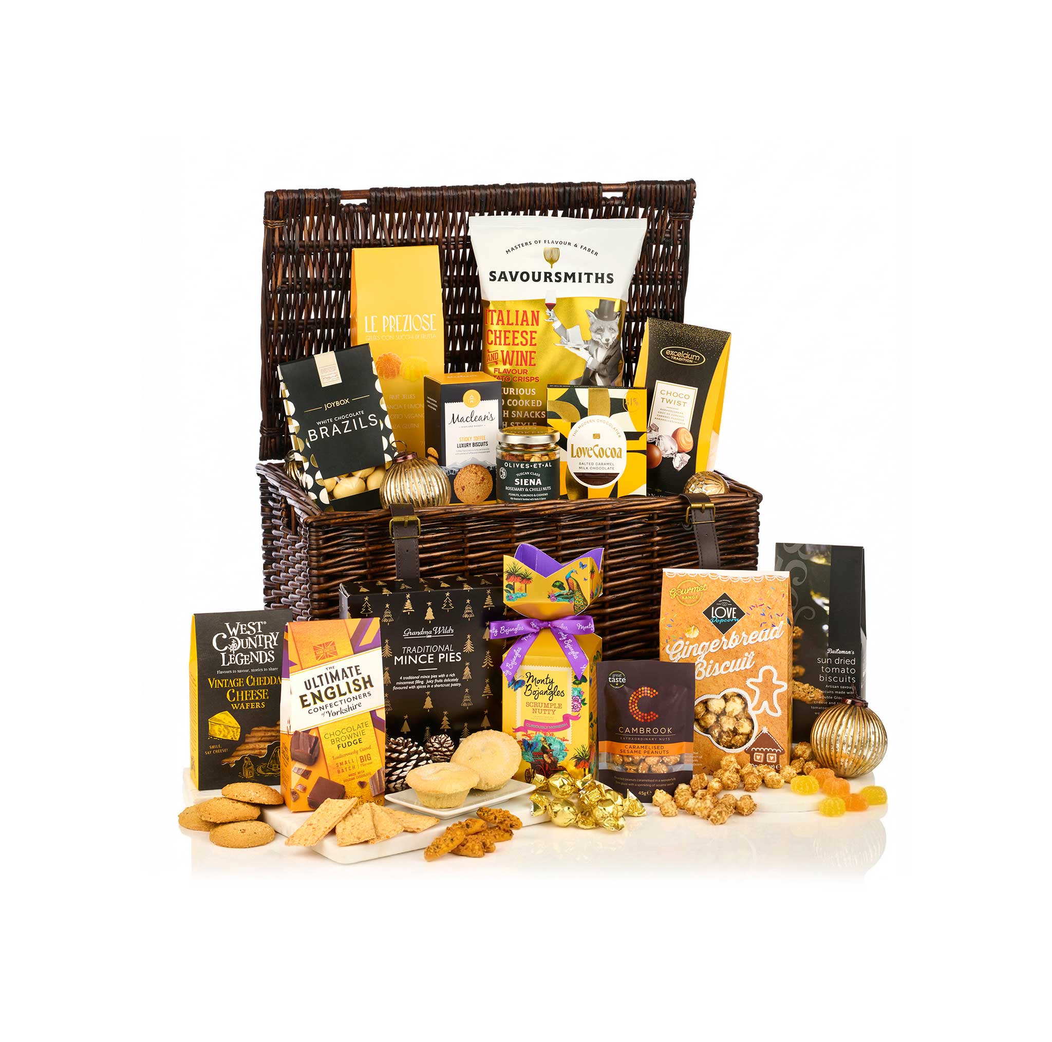 A large gourmet gift hamper filled with assorted packaged snacks, crackers, nuts, and sweets, arranged on a white studio background with some items placed in front of the basket.