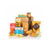 A curated gourmet gift basket filled with assorted snacks and treats, including Trader Joe's Chilli Ginger & Cumin, Raisine chocolate, Lavender & Lime cookies, and Love Popcorn, arranged in front of a brown cardboard gift box on a white background.