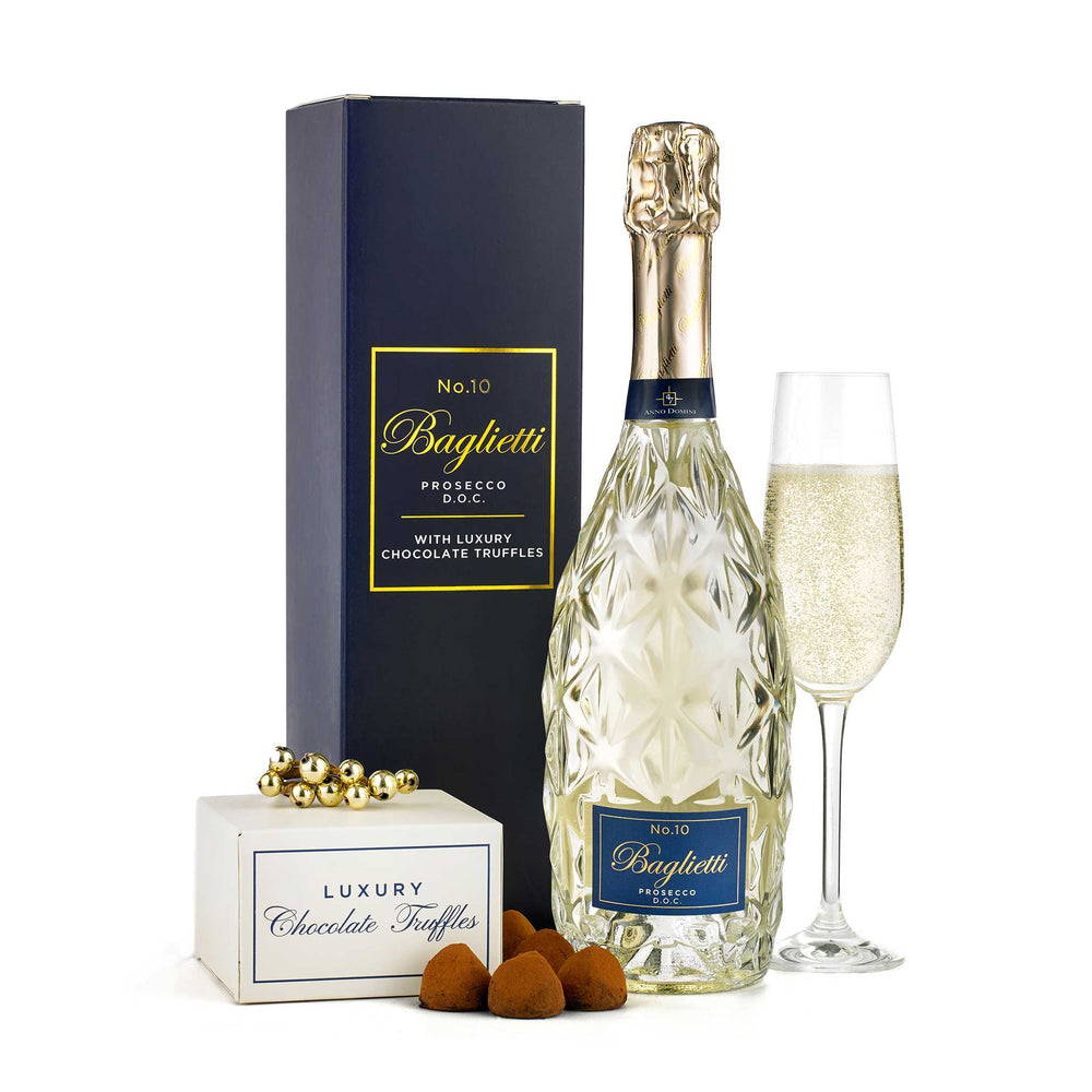 A luxury gift set featuring a bottle of Baguetti No.10 Prosecco, a tall dark blue presentation box, a filled champagne flute, a small box of Baguetti chocolate truffles, and a few truffles placed in front, all on a clean white background.
