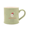 A light sage green ceramic mug with a handle, featuring a graphic of Santa Claus and the text 'SANTA CLAUS is coming to town' on a plain white background.
