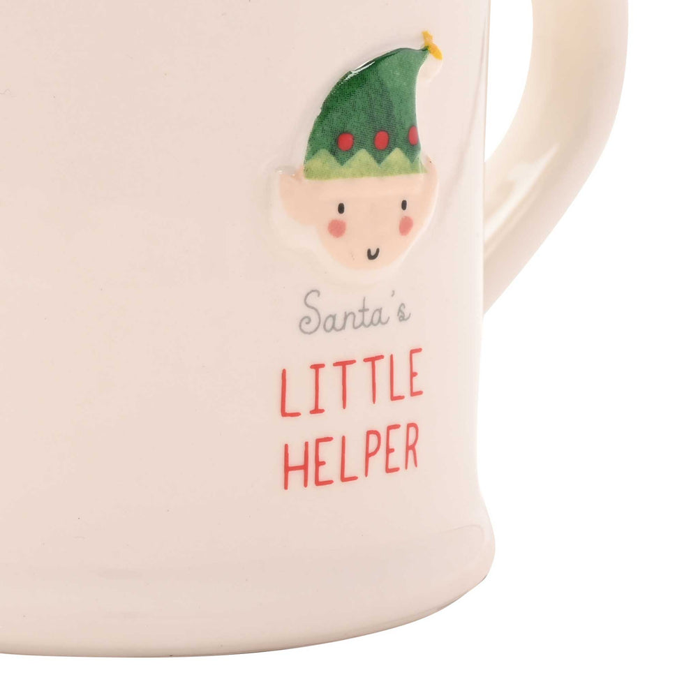 Close-up of a cream-colored ceramic mug featuring a raised relief of Santa's Little Helper elf and the text 'Santa's LITTLE HELPER' in red and gray lettering.