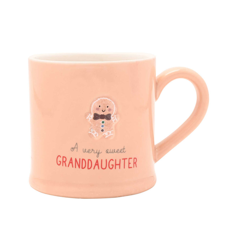 A light peach ceramic mug with a handle, featuring a cute gingerbread man illustration and the text 'A very sweet GRANDDAUGHTER' on a plain white background.